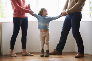 Parents pulling child in separate directions